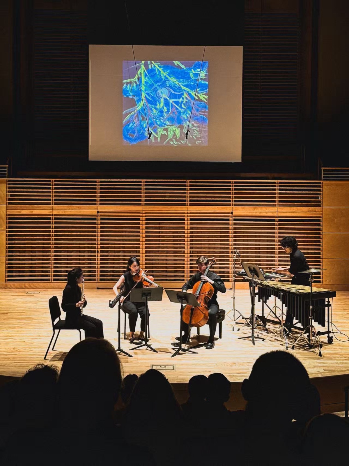 Quartet on stage with a painting projected behind